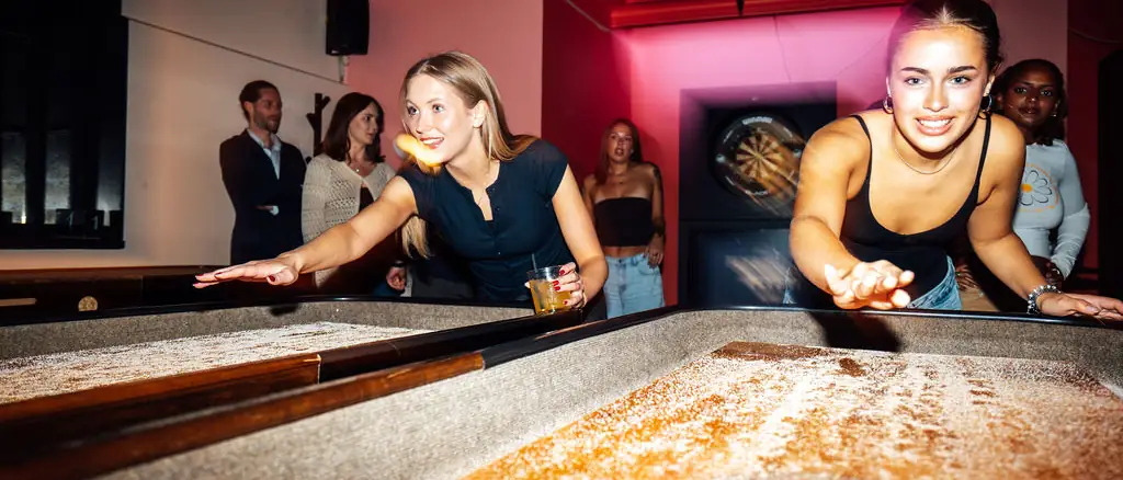 Venner som spiller shuffleboard hos Oslo Bar & Bowling
